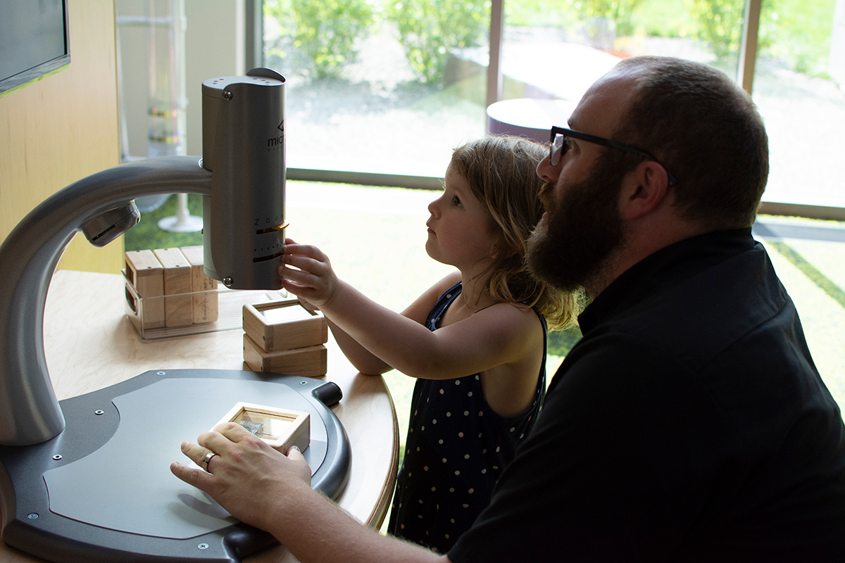 girl and father at a video microscope station